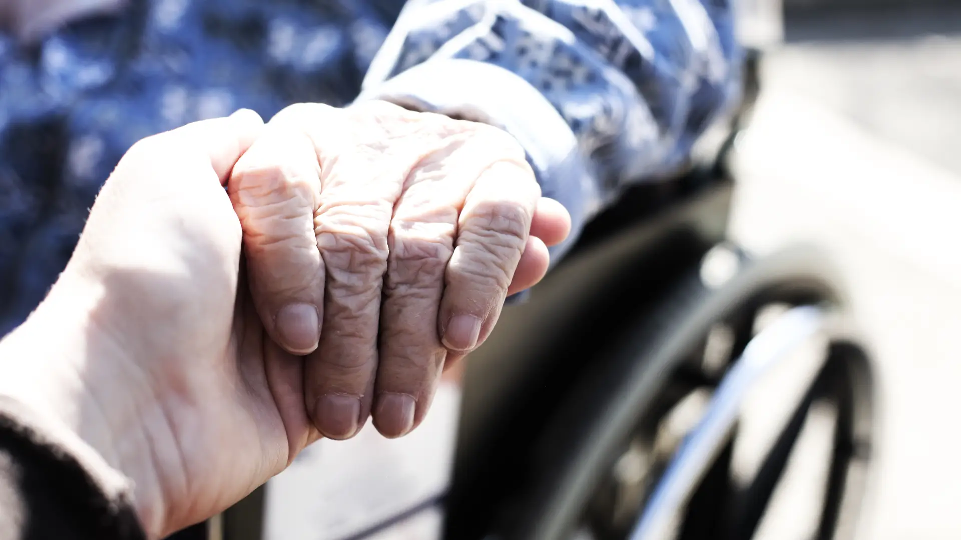 Close up of hands of aged woman sitting in the wheelchair outdoors