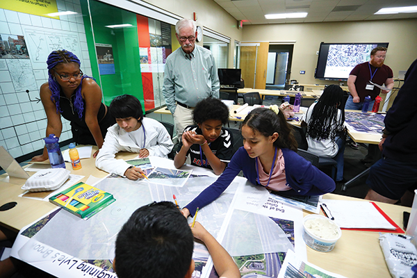 Walter C. “Wally” Evans MCRP ’74 (standing, back center) observes student participants of the Creative Cities Camp during one of their small group sessions in the Bloustein School’s graduate studio space.