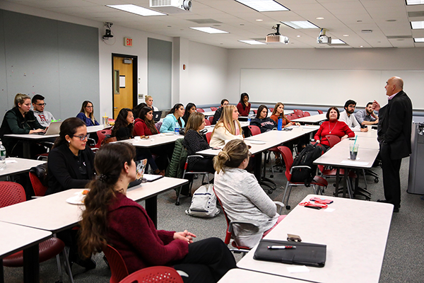 University Professor Emeritus Raphael J. Caprio (far right), founding executive director of the Master of Health Administration program, addresses an early MHA cohort.