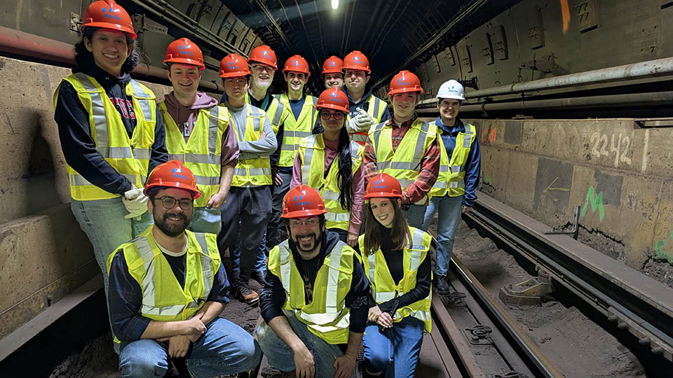 Students wearing yellow reflective vests and orange hardhats participating with Bloustein Enthusiasts and Advocates for Transportation (BEAT) took part in an exclusive after-hours PATH (Port Authority Trans-Hudson) tour.