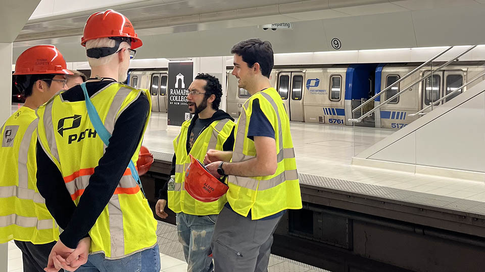 Students wearing yellow reflective vests and orange hardhats participating with Bloustein Enthusiasts and Advocates for Transportation (BEAT) took part in an exclusive after-hours PATH (Port Authority Trans-Hudson) tour.