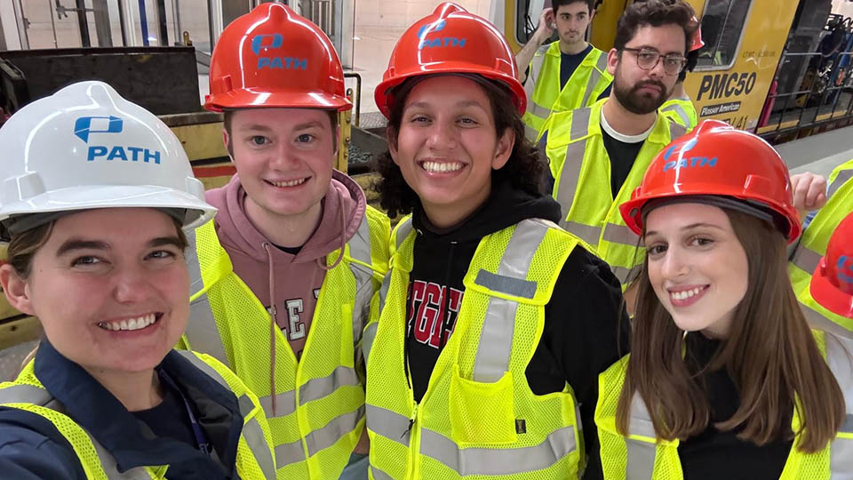 Students wearing yellow reflective vests and orange hardhats participating with Bloustein Enthusiasts and Advocates for Transportation (BEAT) took part in an exclusive after-hours PATH (Port Authority Trans-Hudson) tour.