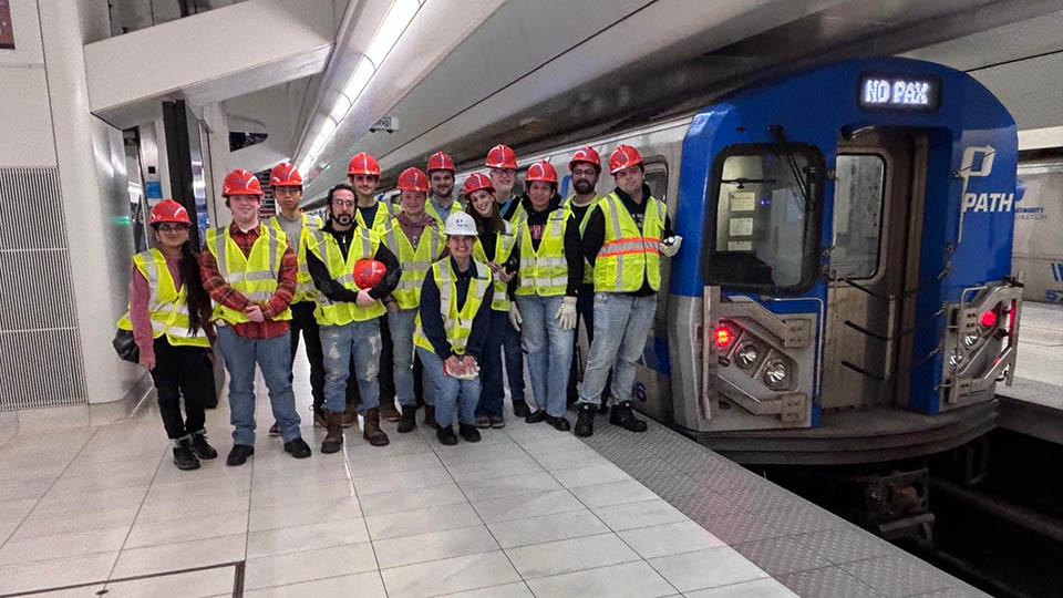 Students wearing yellow reflective vests and orange hardhats participating with Bloustein Enthusiasts and Advocates for Transportation (BEAT) took part in an exclusive after-hours PATH (Port Authority Trans-Hudson) tour.
