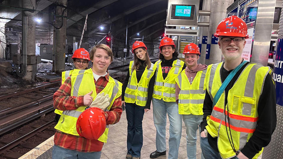Students wearing yellow reflective vests and orange hardhats participating with Bloustein Enthusiasts and Advocates for Transportation (BEAT) took part in an exclusive after-hours PATH (Port Authority Trans-Hudson) tour.